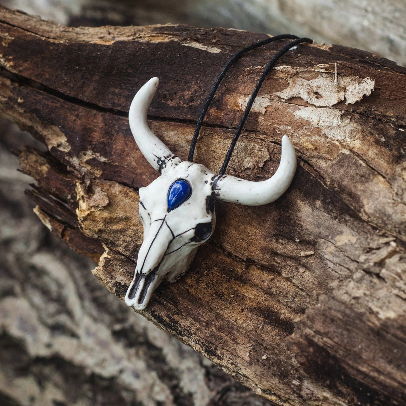 Bull skull pendant decorated with a blue bead