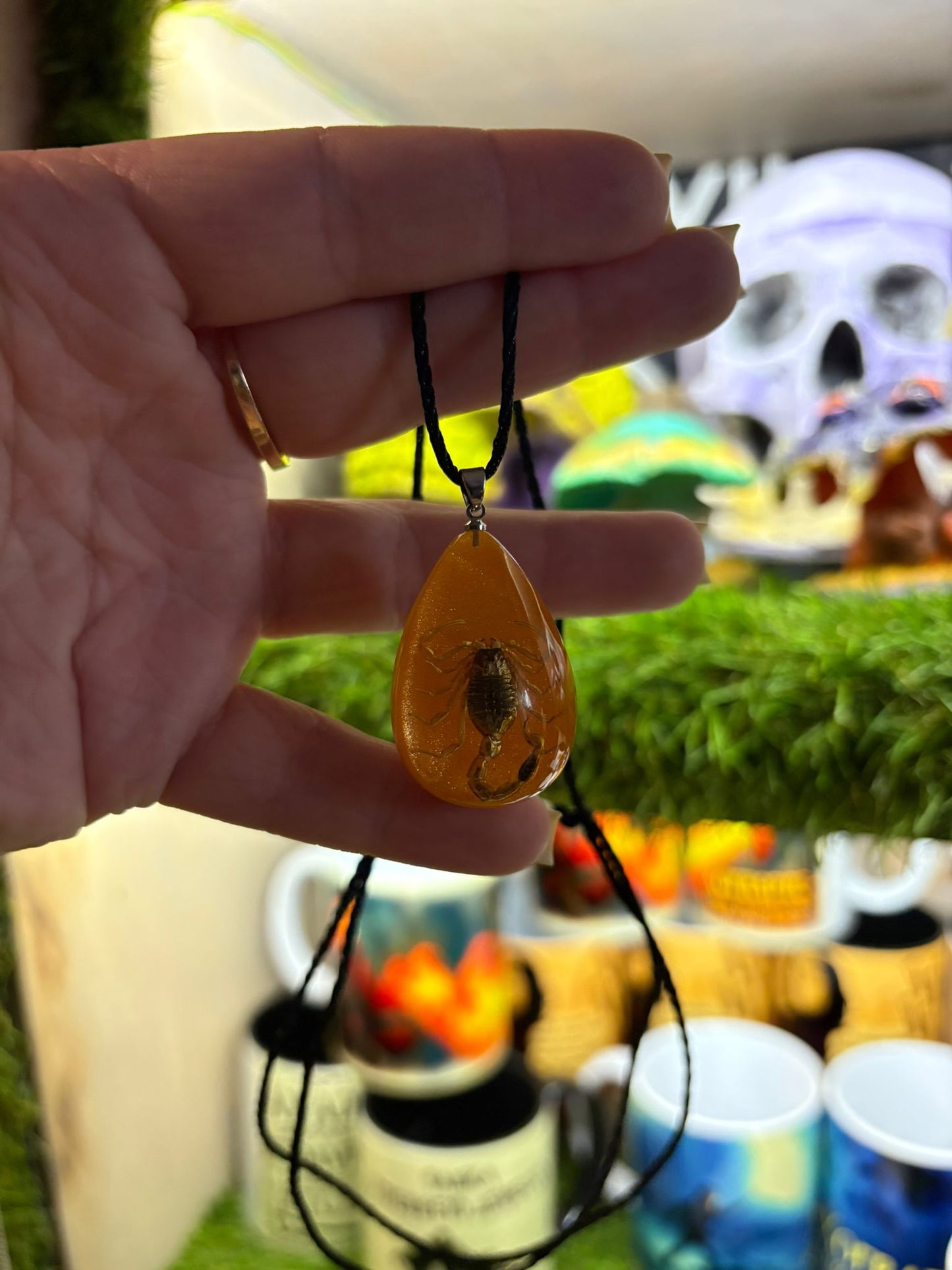 Oranžs mirdzošs kulons ar skorpionu.